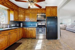 a kitchen with wooden cabinets and a black refrigerator at The Farm Cottage in Burley