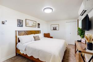 a white bedroom with a bed and a tv at The Farm Cottage in Burley