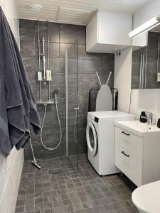 a bathroom with a shower and a washing machine at Brand new loft apartment with glazed balcony in Tampere