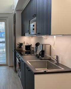 a kitchen with black cabinets and a sink at Brand new loft apartment with glazed balcony in Tampere