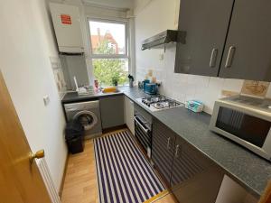 a small kitchen with a stove and a microwave at Spacious Family Flat in London