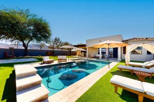 - une piscine avec des chaises et des parasols à côté d'une maison dans l'établissement Mountain Vista Overlook, à Phoenix