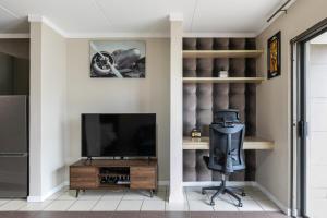a living room with a television and a chair at Dainfern K Luxe Apartment in Sandton