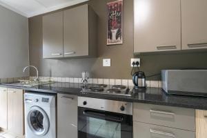 a kitchen with a stove and a washer and dryer at Dainfern K Luxe Apartment in Sandton