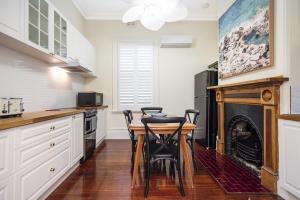 cocina con mesa, sillas y chimenea en Crepe Myrtle Cottage, en South Fremantle