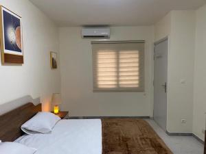 a white bedroom with a bed and a window at CHEZ CODOU FANN RESIDENCE in Dakar