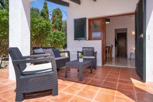 eine Terrasse mit Korbstühlen und einem Tisch in der Unterkunft Villa BINIKIXA in Binibeca