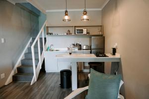 a small kitchen with a desk and a staircase at Thyme Out Weltevreden Farm in Curryʼs Post