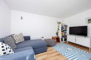 a living room with a blue couch and a flat screen tv at Veeve - Soulful Smiles in London