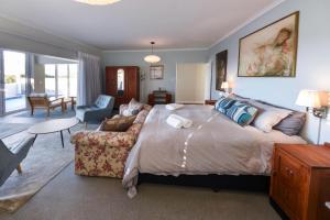 ein Schlafzimmer mit einem großen Bett und einem Sofa in der Unterkunft Die Badhuis, for Fabulous living! Sleeps 4, Private pool in Gordonʼs Bay