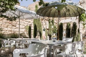 un patio con tavoli, sedie e ombrellone di Jardines de Colón ad Alcalá la Real