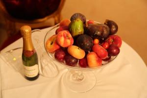 a bowl of fruit on a table with a bottle of champagne at Hotel Scilla in Scilla