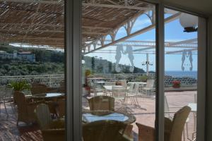 a patio with tables and chairs and a view of the ocean at Hotel Dania in Sorrento