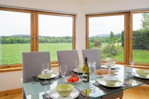una sala da pranzo con tavolo, sedie e finestre di Burnbrae Lodge - Seasgair Lodges a Carrbridge