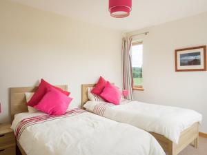 2 letti in una camera con cuscini rosa di Burnbrae Lodge - Seasgair Lodges a Carrbridge