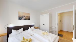 um quarto com uma cama branca com lençóis brancos e flores amarelas em Apartmenthaus Binzer Sterne Haus 1 em Binz