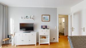 uma sala de estar com televisão numa cómoda branca em Apartmenthaus Binzer Sterne Haus 1 em Binz
