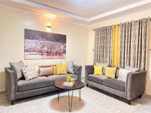 a living room with two couches and a table at Exquisite two bedroom Penthouse-Fully Furnished in Kitale