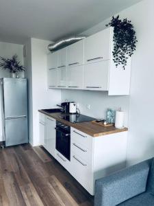 a kitchen with white cabinets and a sink and a refrigerator at Apartament Stary Szczecin in Szczecin