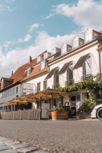 a white building with umbrellas in front of it at Weinforum Franken Hotel & Restaurant in Eibelstadt