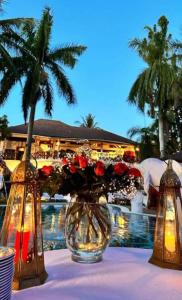 een vaas met bloemen op een tafel naast een zwembad bij African House Resort in Malindi