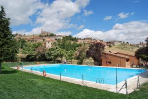 a large blue swimming pool in a field with buildings at La Casa de San Gil in Atienza