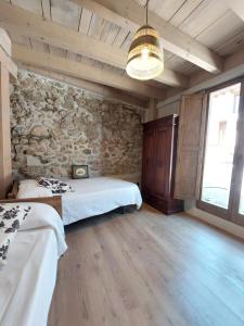 a room with two beds and a stone wall at Turisme Rural Ca l'Axai casa 2 in Pi
