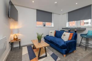 a living room with a blue couch and a tv at Thornhill House Serviced Apartments in Wakefield