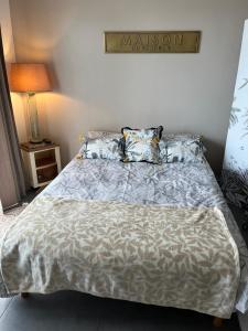 a bedroom with a bed with a gray comforter and pillows at Superbe studio 34m2 avec terrasse aperçu mer in Sanary-sur-Mer