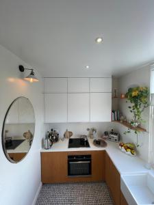 een keuken met witte kasten en een spiegel bij Grand appartement Haussmannien à 12 min de Paris - Proche Stade de France - Jeux Olympiques 2024 in Enghien-les-Bains