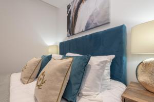a bedroom with a blue headboard and pillows on a bed at Thornhill House Serviced Apartments in Wakefield