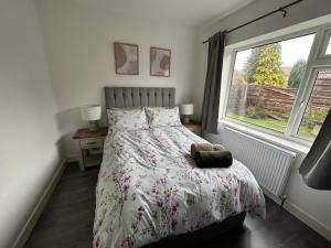 1 dormitorio con cama y ventana en Roomy 3 BR bungalow in Sale, with Parking MCR, en Broadheath