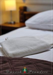 2 camas blancas con una toalla encima en Dworek Prawdzic Niechorze, en Niechorze