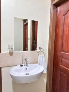 lavabo blanco en el baño con espejo en Exquisite two bedroom Penthouse-Fully Furnished at 360 Luxury, en Kitale