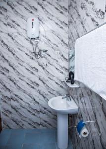 baño con lavabo blanco y pared de piedra en Magnifique Appartement - Cotonou - Avotrou Apkapka en Cotonú