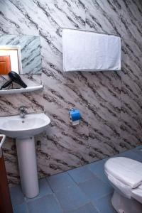 a bathroom with a white sink and a toilet at Magnifique Appartement - Cotonou - Avotrou Apkapka in Cotonou