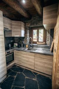 d'une cuisine avec des placards en bois, un évier et une fenêtre. dans l'établissement La grange du hameau, à Saint-Lary-Soulan