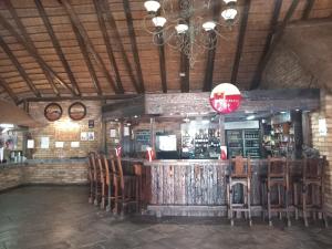 a bar in a restaurant with wooden tables and chairs at Pepe Piatto Lodge in Grootvlei