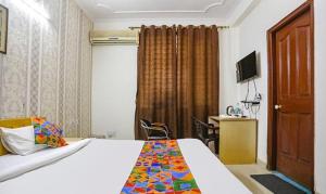 um quarto com uma cama, uma secretária e uma televisão em FabExpress AP International em Noida