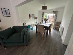 a living room with a green couch and a table at Roomy 3 BR bungalow in Sale, with Parking MCR in Broadheath