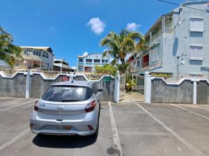 a white car parked in a parking lot next to a building at Plein Soleil in Grand Baie
