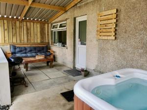 a tub in a patio with a couch and a table at Glenariff Forest Getaway in Glenariff