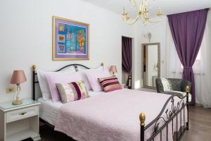 1 dormitorio con 1 cama con cortinas moradas y lámpara de araña en Romantic Luxury Rooms, en Split