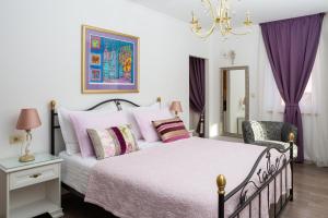 een slaapkamer met een bed met paarse gordijnen en een kroonluchter bij Romantic Luxury Rooms in Split