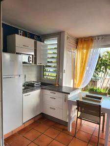 eine Küche mit weißen Schränken, einem Tisch und einem Fenster in der Unterkunft Anse des rochers - Ti Kaz MiLouMa in Saint-François