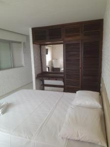 uma grande cama branca num quarto com uma janela em Hotel Sambura em Imbé