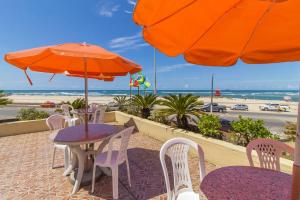 einen Tisch und Stühle mit Sonnenschirmen und den Strand in der Unterkunft Hotel Sambura in Imbé
