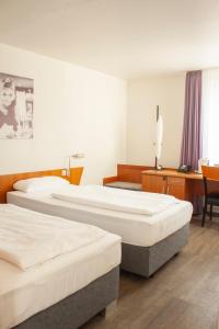 a hotel room with three beds and a desk at hogh Hotel Heilbronn in Heilbronn