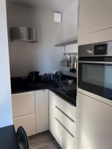 een keuken met witte kasten en een zwarte oven bij Studio indépendant in Vence