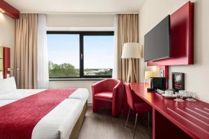 a hotel room with a bed and a desk with a tv at Amedia Amsterdam Airport Schiphol, Trademark Collection by Wyndham in Schiphol